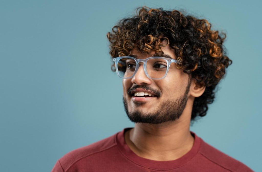 A smiling man wearing blue, transparent eyeglass frames.
