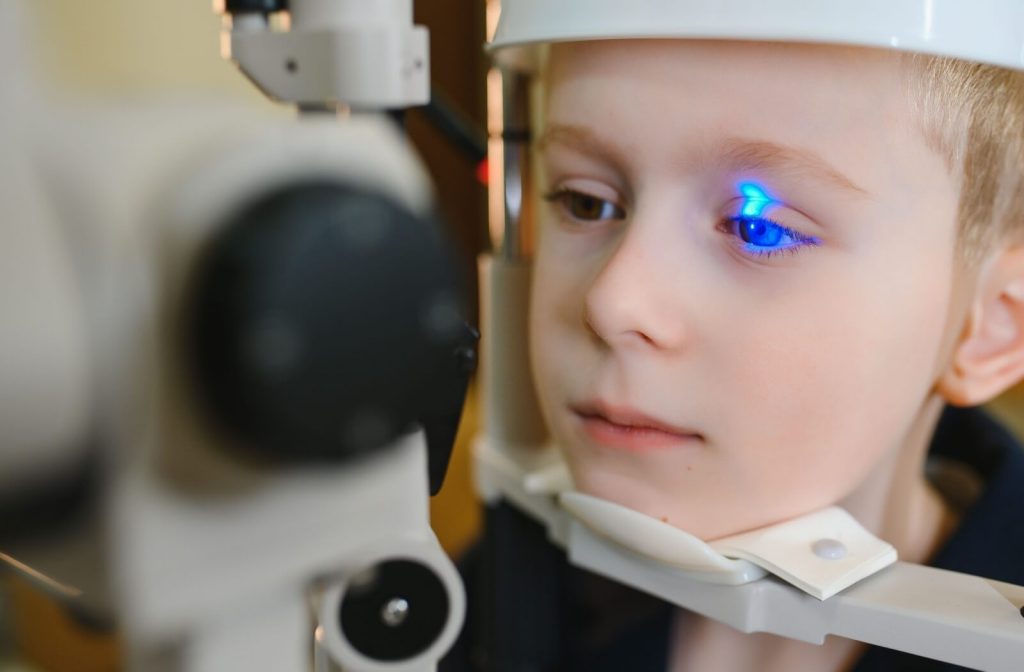 Child undergoing a pediatric eye exam with an optometrist using a slit lamp, highlighting the importance of early eye exams for children’s vision health.